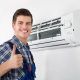 un installateur qui lève son pouce vers le haut et derrière il y a une climatisation